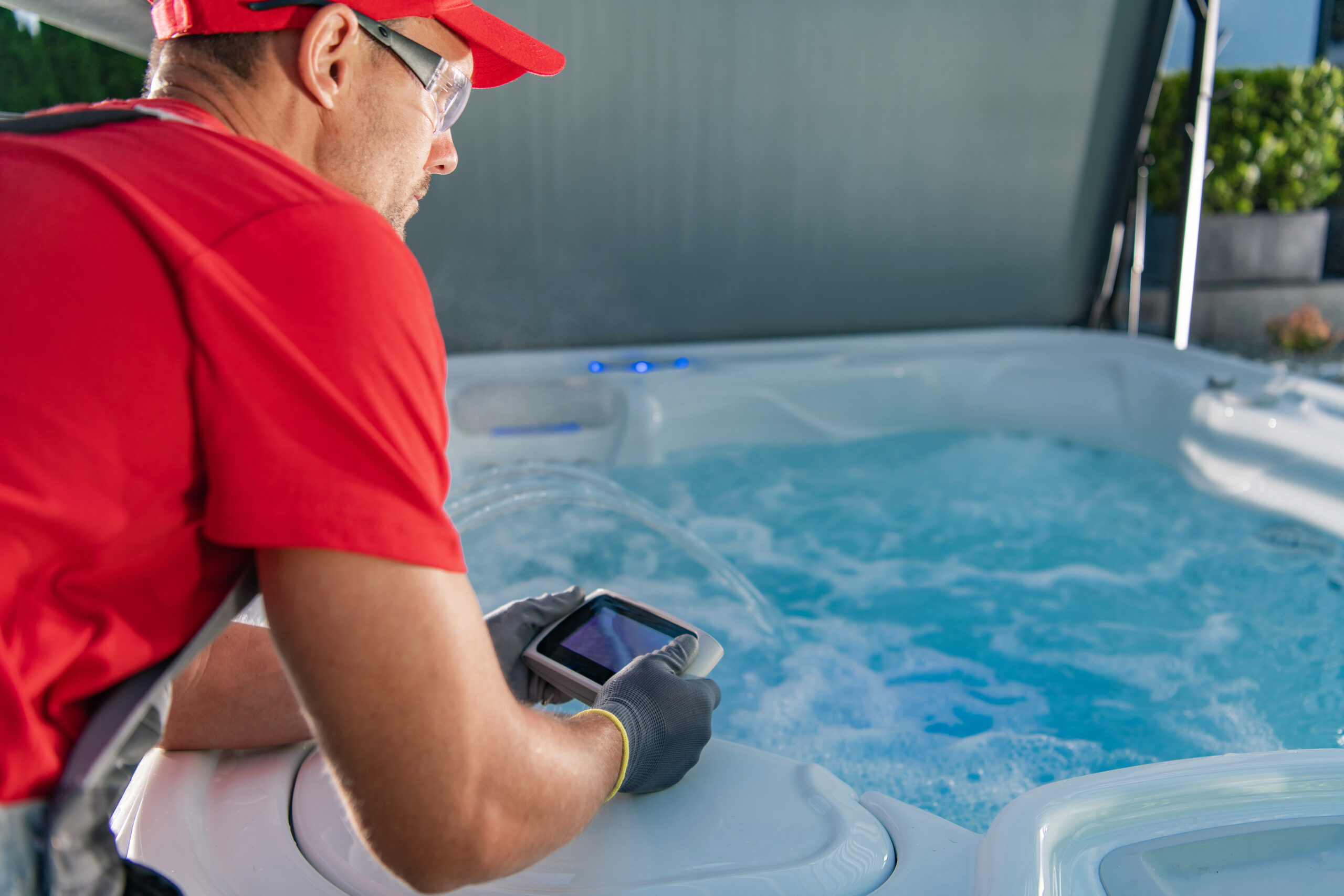 Technicien vérifiant le jacuzzi avec un appareil électronique.