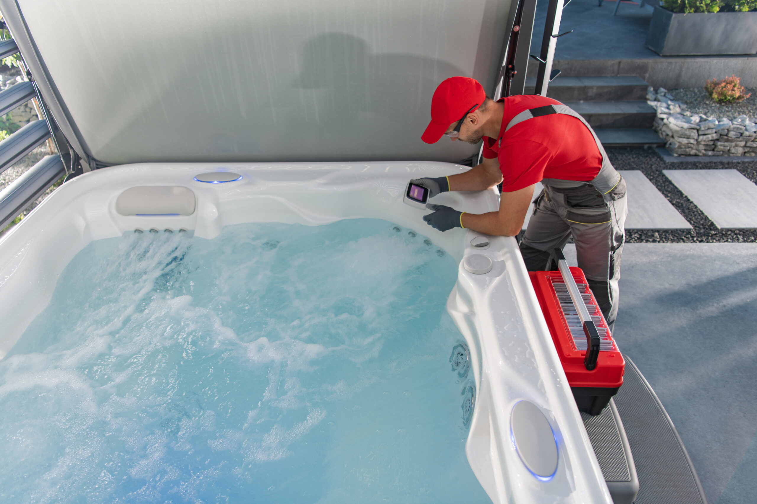 Technicien vérifiant l'eau d'un jacuzzi extérieur.