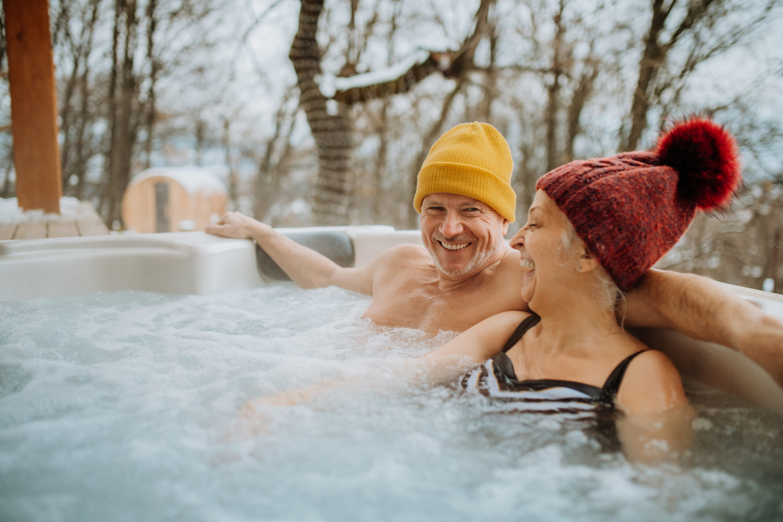 Couple souriant dans un jacuzzi en hiver